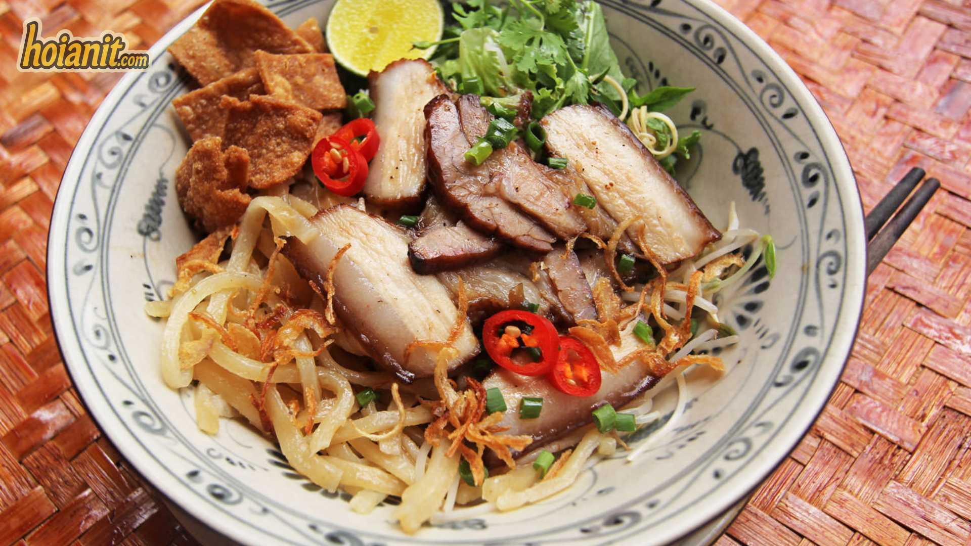 Cao Lau Hoi An 4 Cao lau bowl on a woven mat with chilli, lime and crisp fried squares ready to be tossed