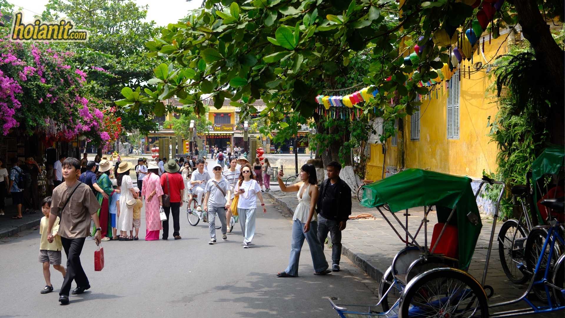 Crowds and a parked cyclo on a busy Old Town street — the opposite of slow travel in Hoi An