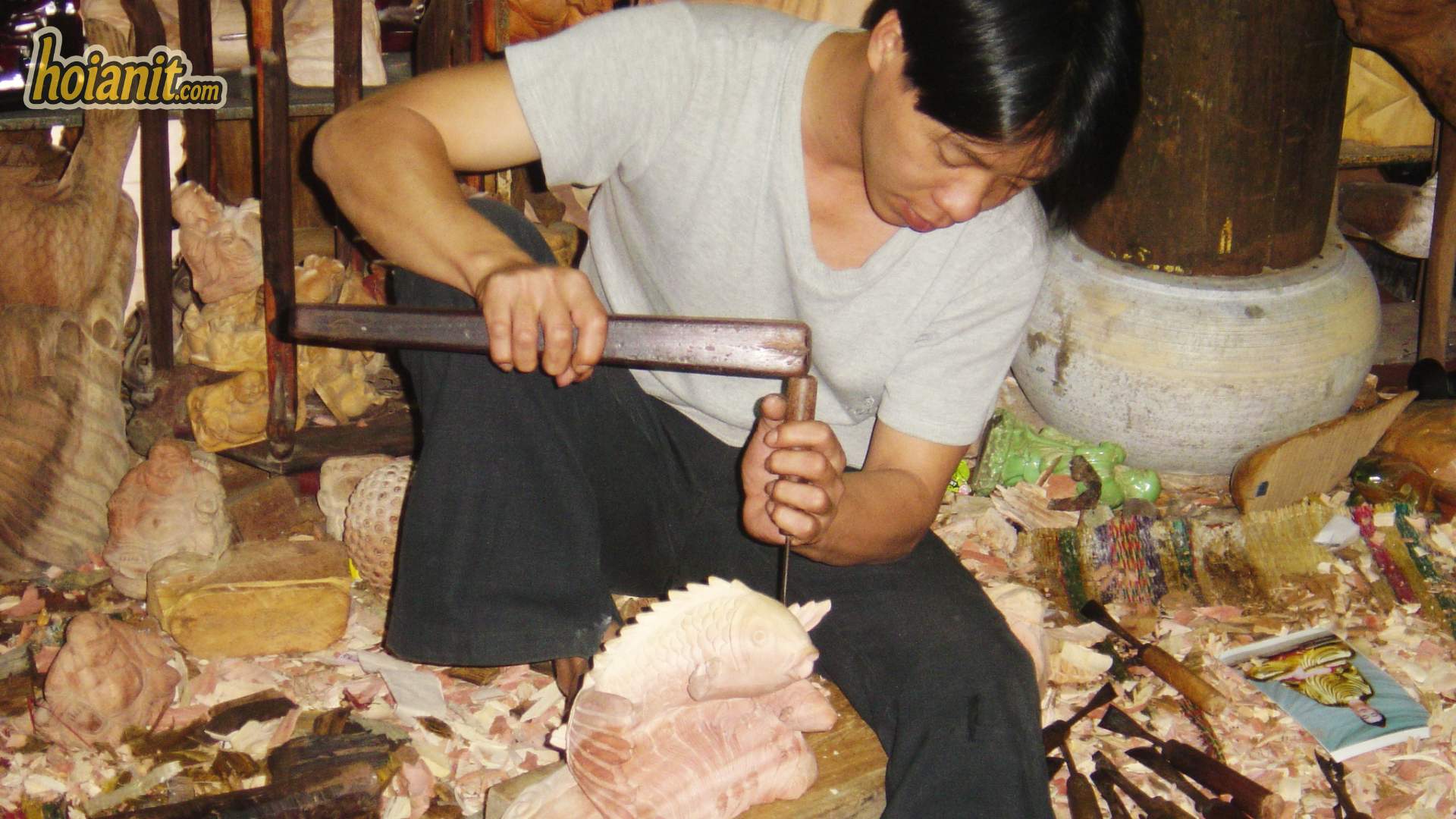 Nghệ nhân làng mộc Kim Bồng ngồi chạm khắc tượng gỗ bằng đục trong xưởng