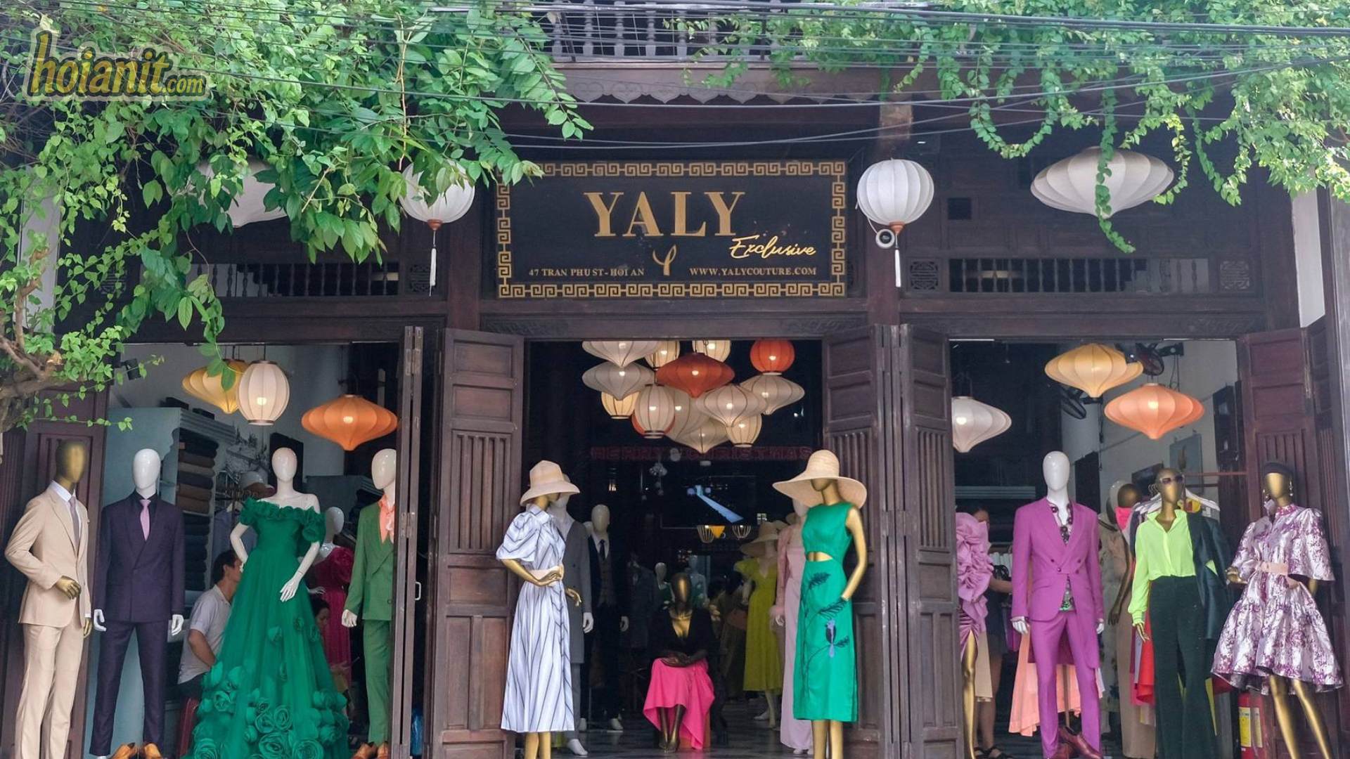 Rolls of suiting fabric and a tailor taking measurements at one of the best tailors in Hoi An