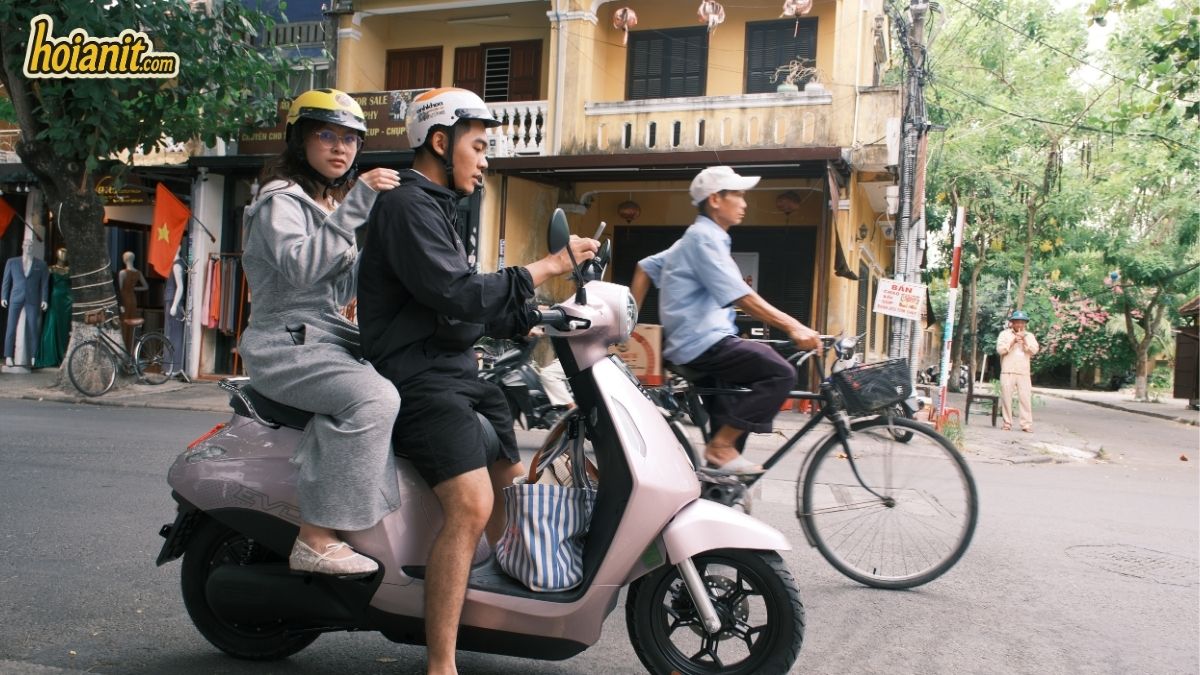 Pareja en scooter eléctrico rosa por las calles del casco antiguo de Hoi An