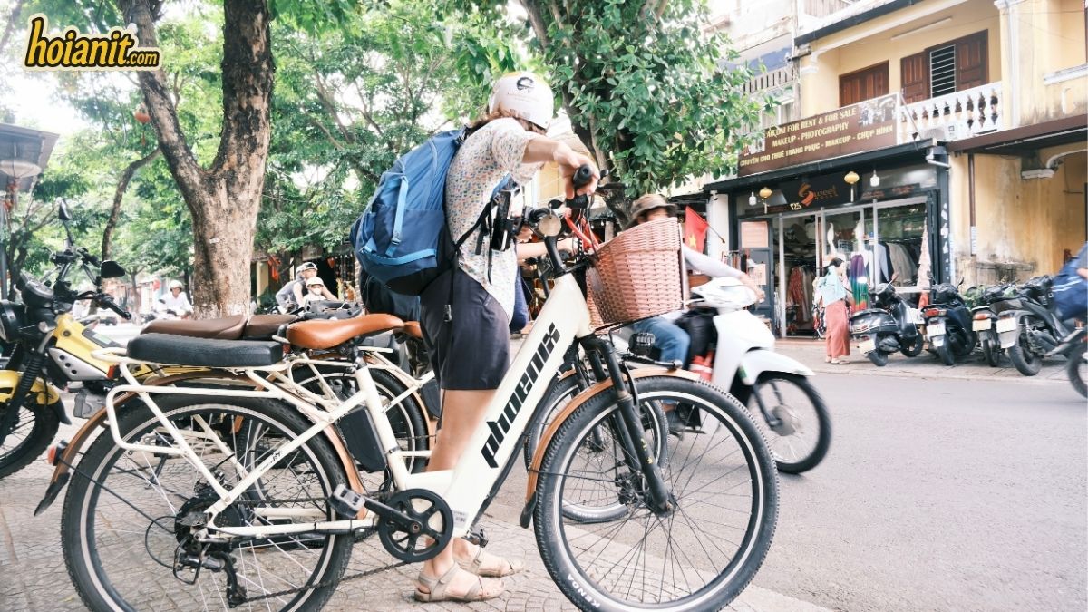 Turista eligiendo una bicicleta eléctrica Phoenix con cesta en Hoi An