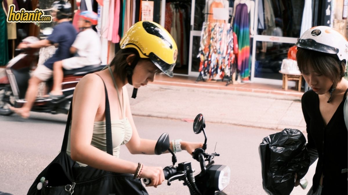 Clienta con casco amarillo recibiendo su scooter eléctrico en Hoi An