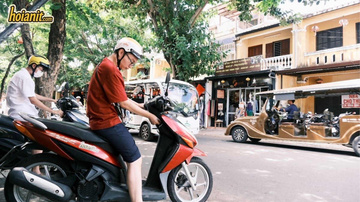 Turista con casco subiendo a una Honda Air Blade de hoianit.com en Hoi An