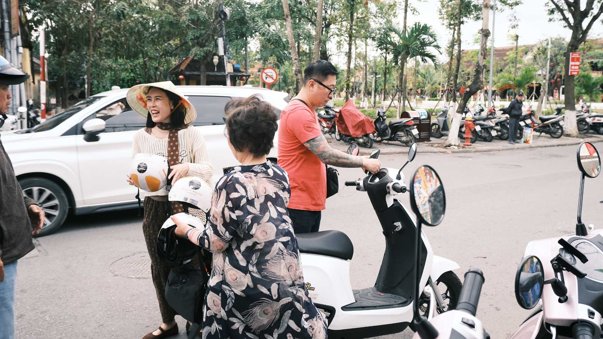 Family with a white VinFast Evo electric scooter on a Hoi An street, a no A1 license option