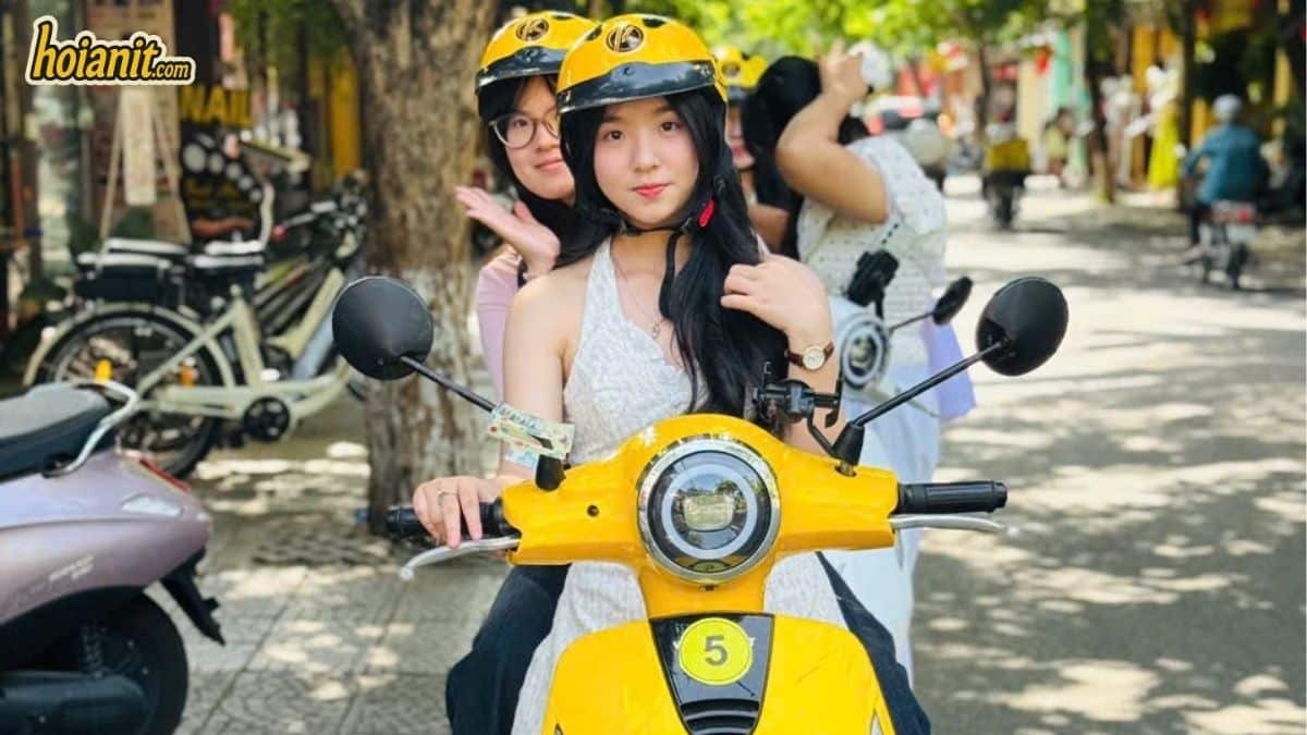 Two riders on a yellow electric scooter rented from Anh Khoa in Hoi An