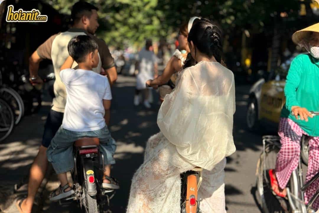 Riders and pedestrians sharing a tree-lined road out of Hoi An