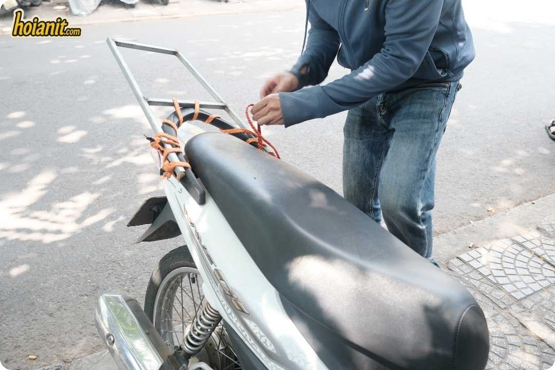 bike rental hoi an3 5 Mechanic securing the rear rack strap on a scooter before a rental