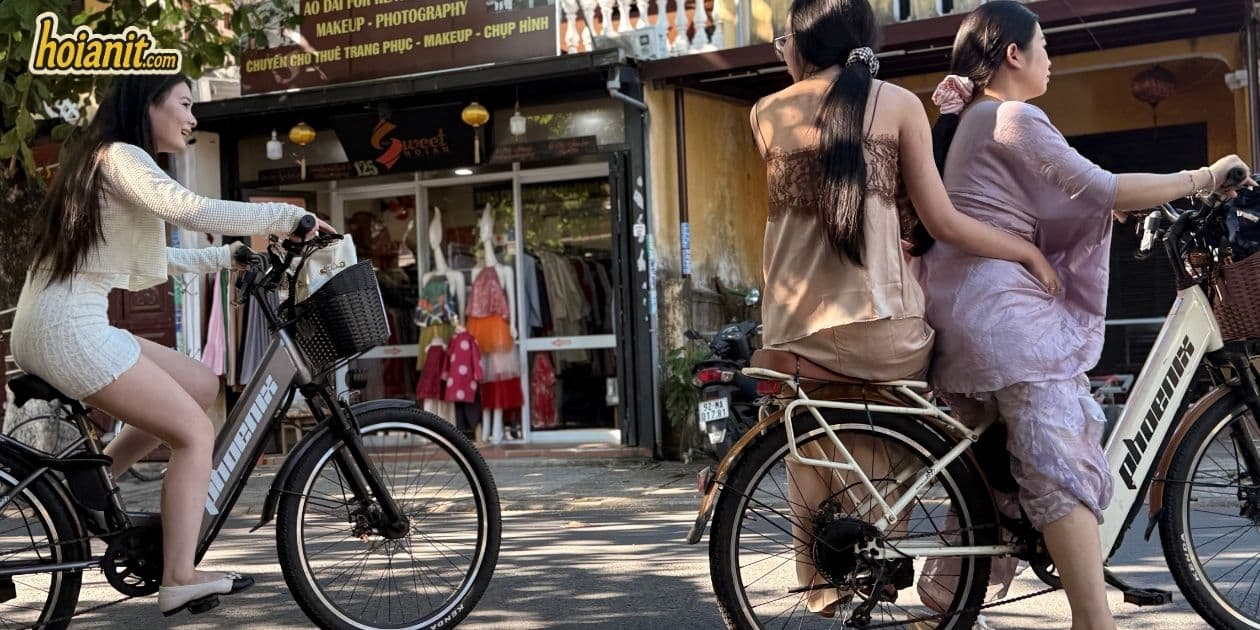 Electric bicycles passing an ao dai rental shop in Hoi An Ancient Town