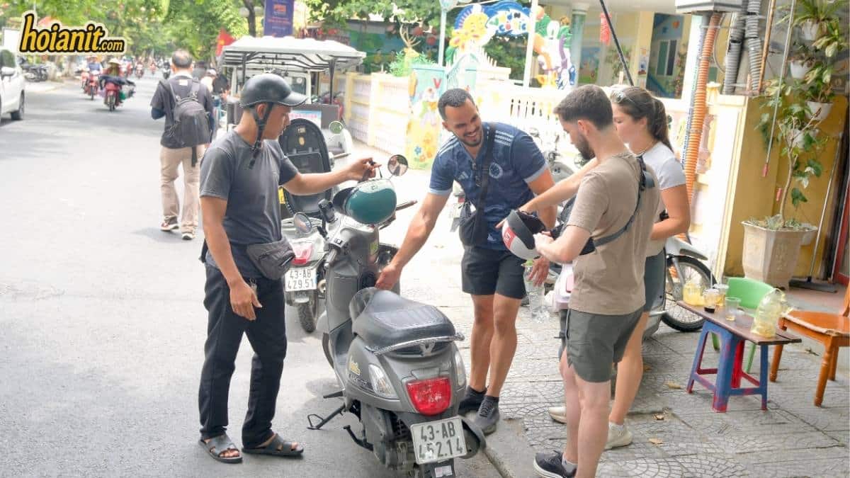 Contact motorbike rental Hoi An: staff handing over a scooter and helmets on the street