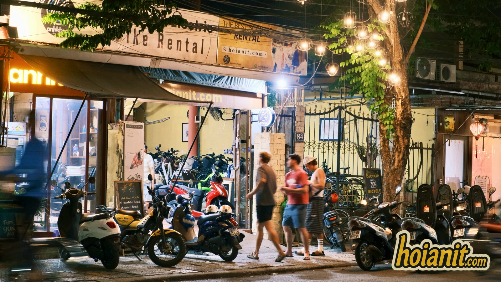 Anh Khoa bike rental shop front in Hoi An in the evening with tourists walking past