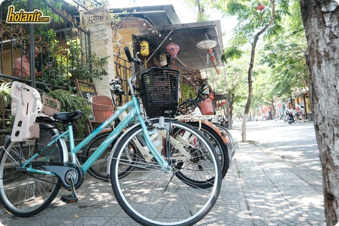 Bicycles with baskets and a child seat parked outside Anh Khoa bike rental in Hoi An