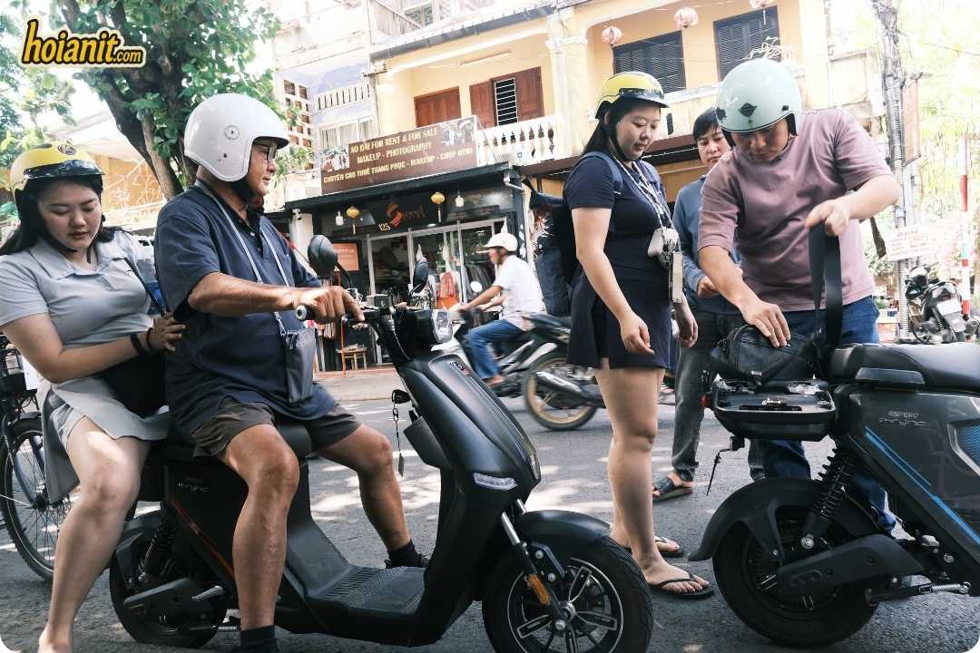 Anh Khoa staff fitting helmets on a group of customers before a scooter rental in Hoi An