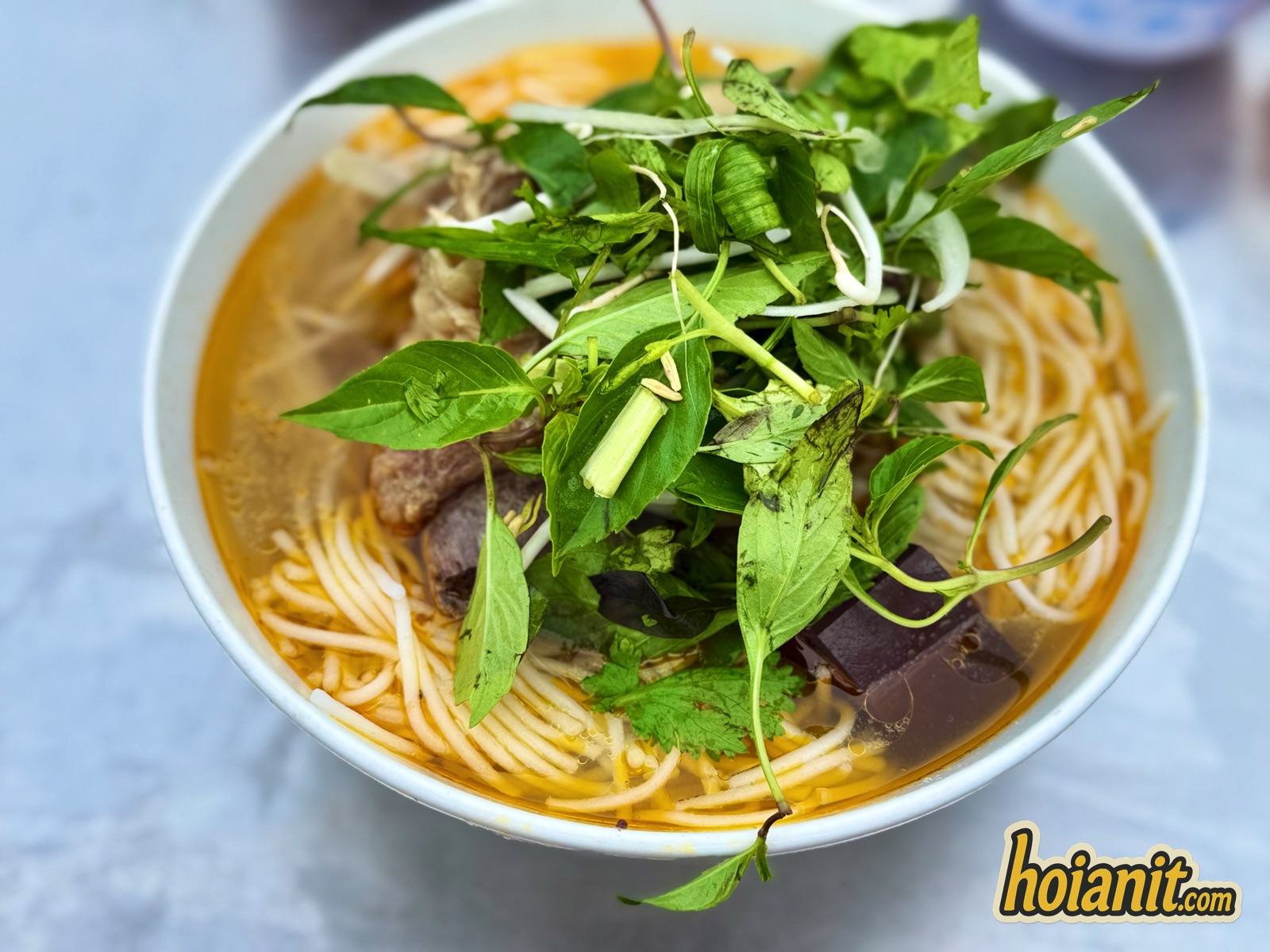 Tô bún bò Hội An tại Bún Nhâm với thịt bò, huyết, rau húng quế và giá