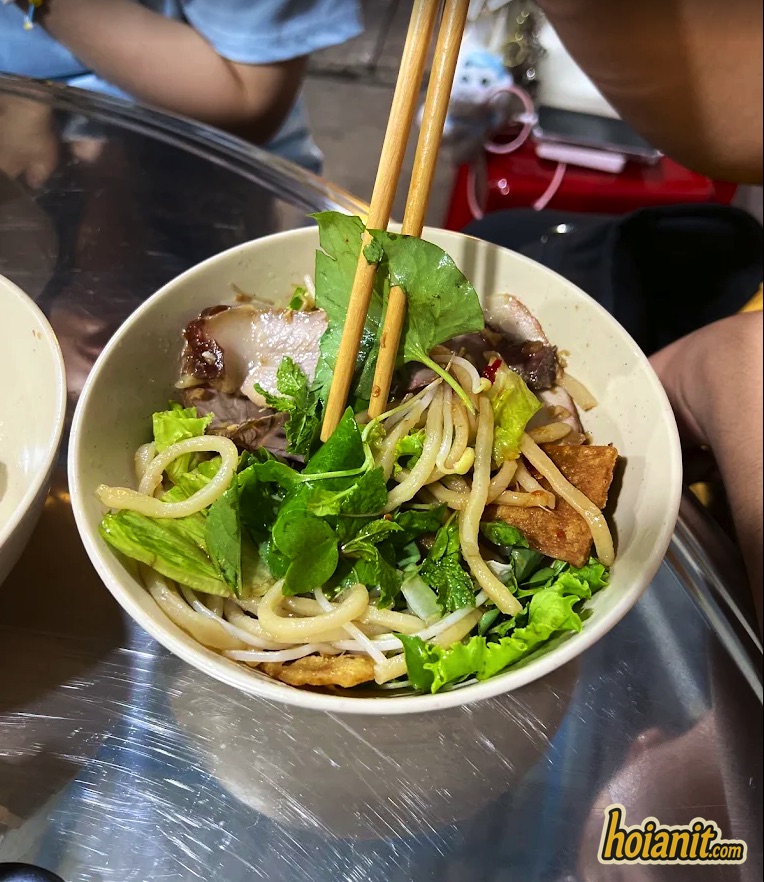 A bowl of cao lau at Cao Lau Thuong Hoi An with pork, crackling, herbs and chopsticks