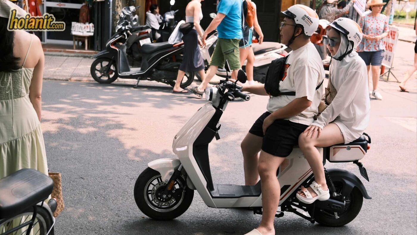 couple riding mini scooter white scooter hoi an street helmets Cặp đôi đội mũ bảo hiểm chạy Mini Electric Scooter trắng trên phố Hội An