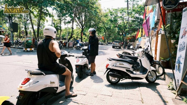 Couple riding VinFast evo scooter Hoi An street black helmet