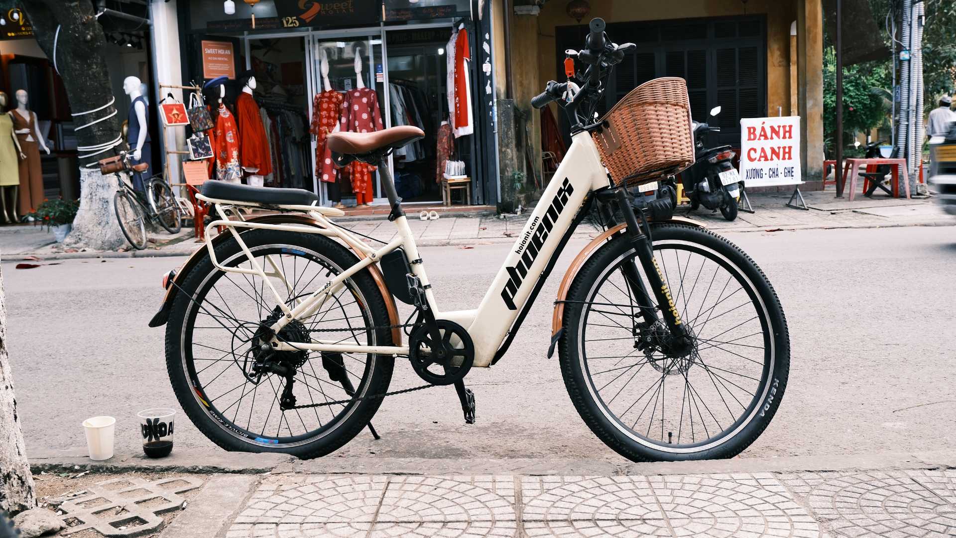 electric bicycle white brown basket side hoi an street Xe đạp điện trợ lực màu trắng có giỏ mây dựng trên phố Hội An