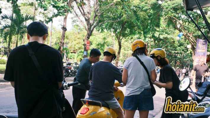 Group tourists renting scooters Hoi An yellow helmets