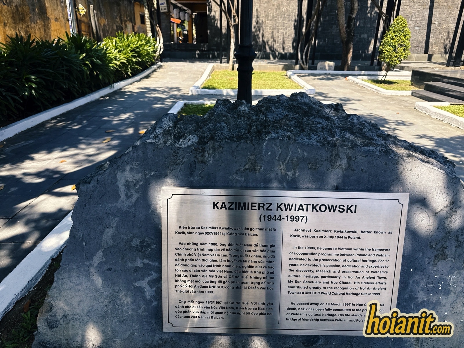 Bilingual biography plaque of Kazimierz Kwiatkowski (1944-1997) on a stone in Kazik Park Hoi An