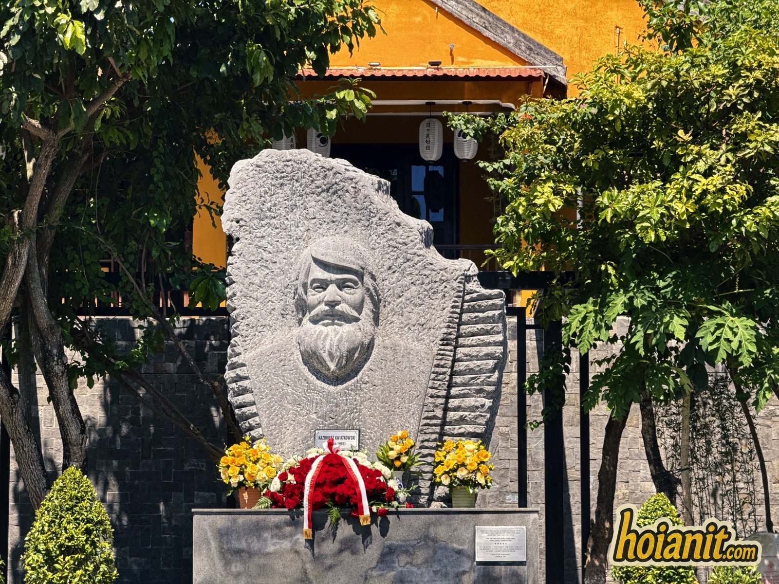 Kazik statue in Hoi An, a carved stone relief with flowers and a wreath on the base