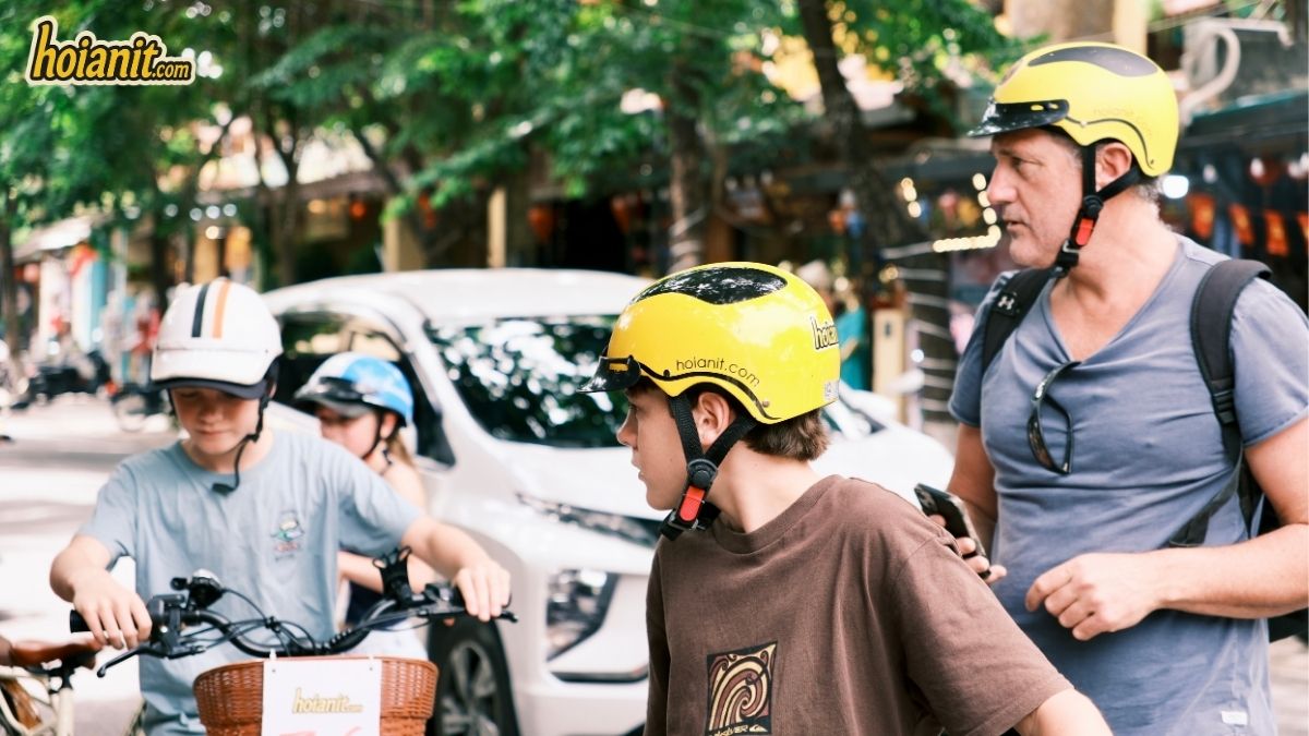 Famille avec casques jaunes hoianit.com louant des vélos dans la vieille ville de Hoi An