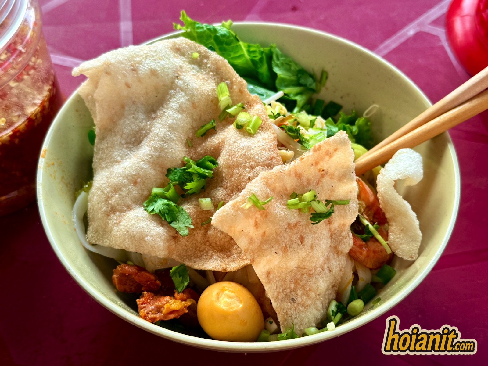 Bowl of mi Quang at Ba Tung stall in Hoi An with grilled rice cracker, quail eggs and herbs