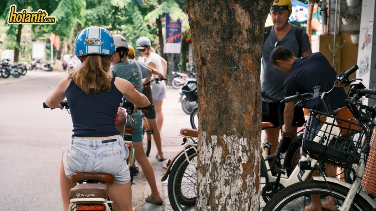 Travellers wearing hoianit.com branded helmets on rental bikes in Hoi An