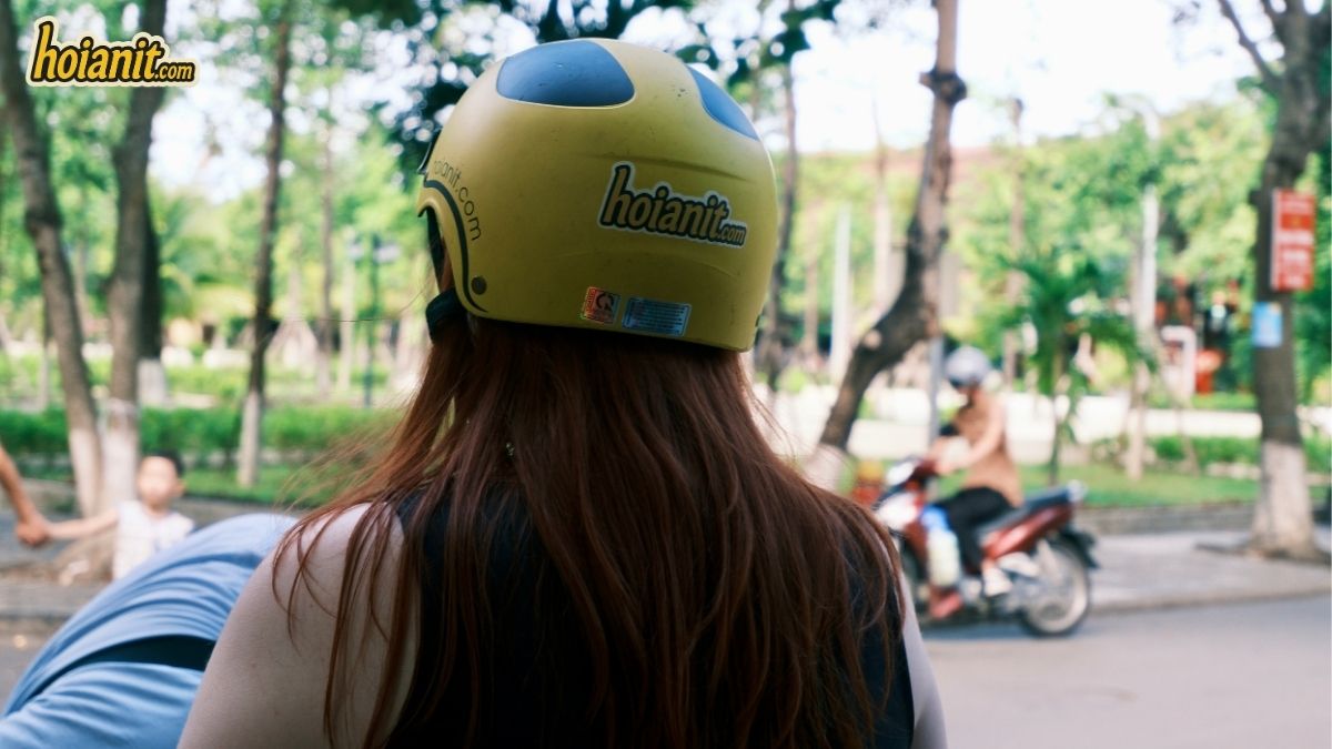 Traveller riding a rental motorbike through Hoi An wearing an Anh Khoa helmet