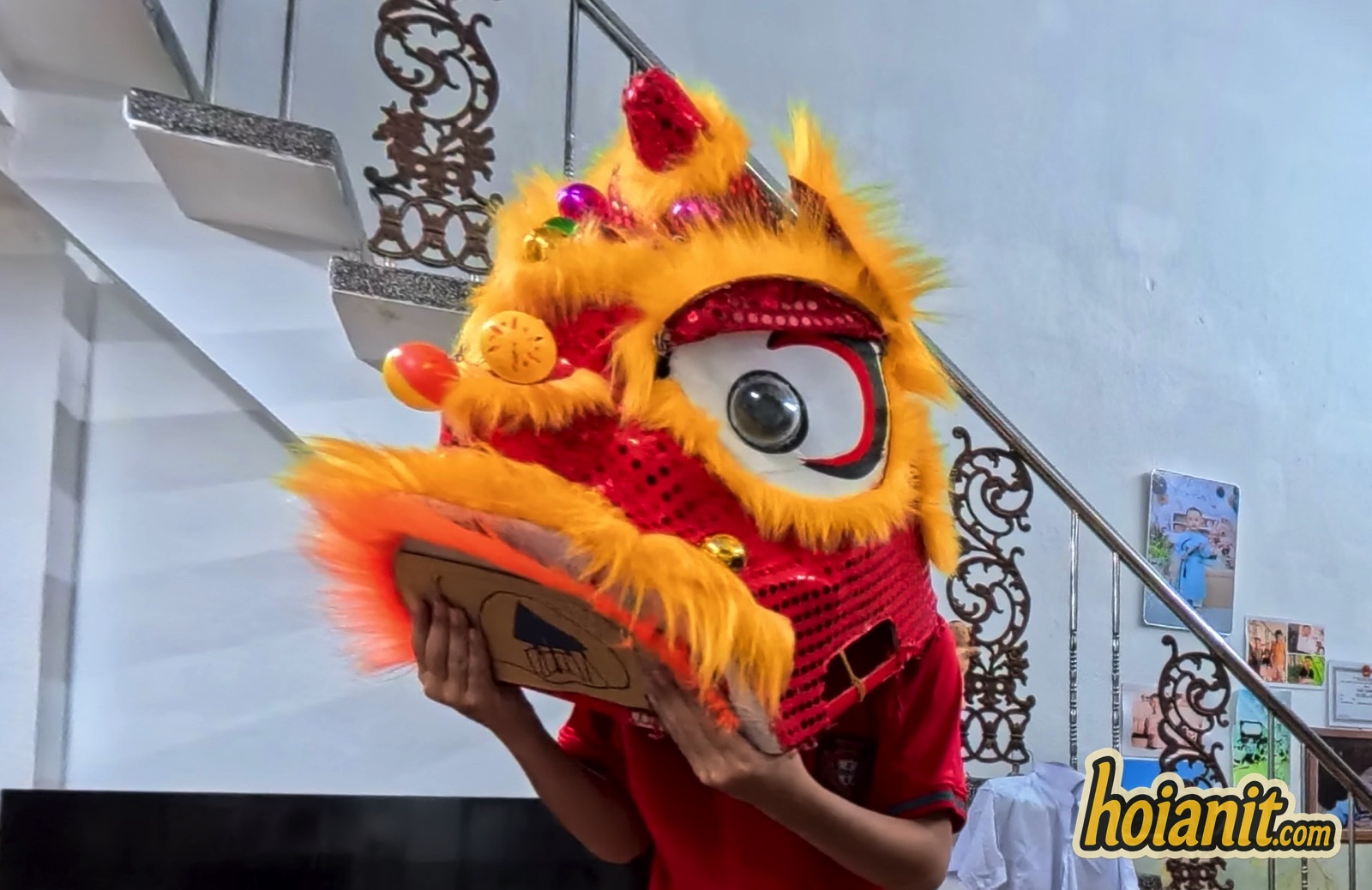 Child wearing a small lion dance head at home during the Mid-Autumn Festival in Hoi An