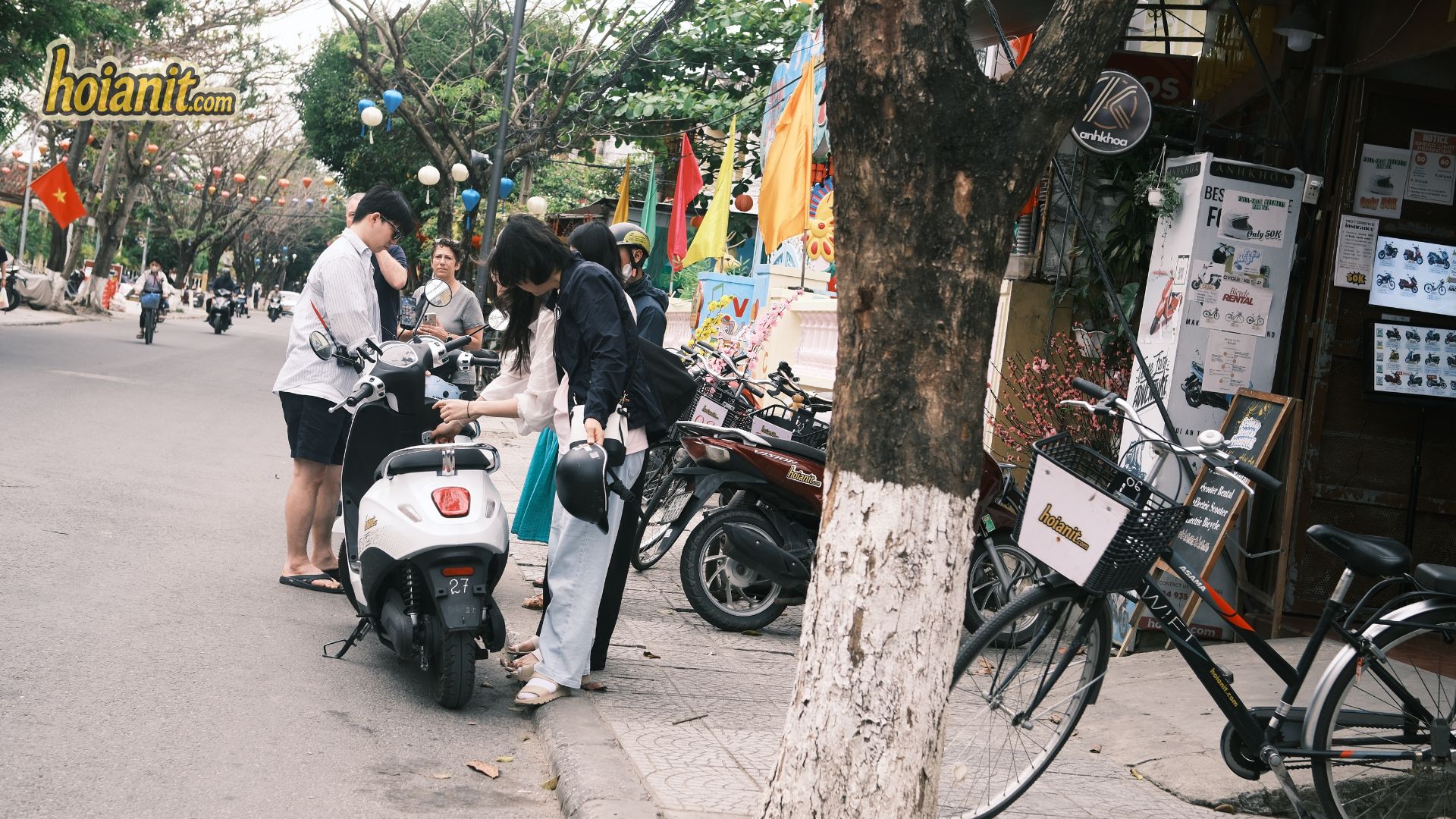 Tourist collecting a no-license electric scooter outside the rental shop in Hoi An
