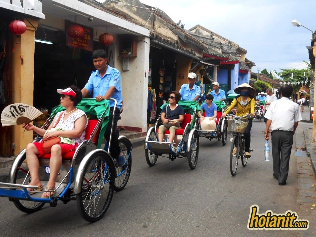Đoàn xích lô Hội An chở khách du lịch chạy qua dãy nhà cổ trong phố cổ