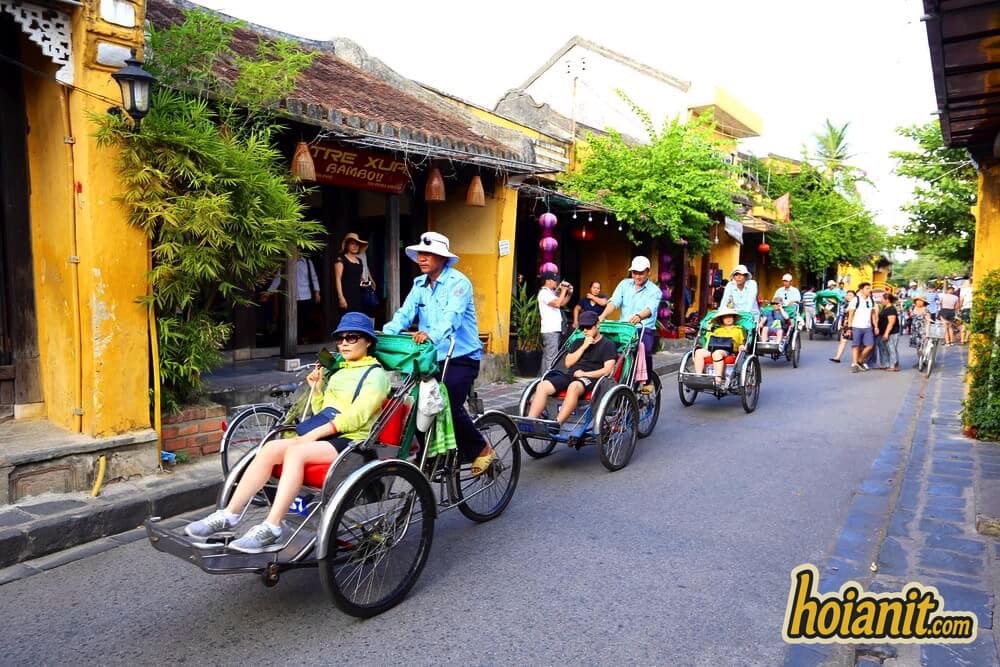 Xích lô Hội An nối đuôi nhau trên đường Trần Phú, hai bên là hàng quán và đèn lồng